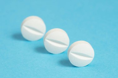 Mavi arka planda üç beyaz aspirin tableti