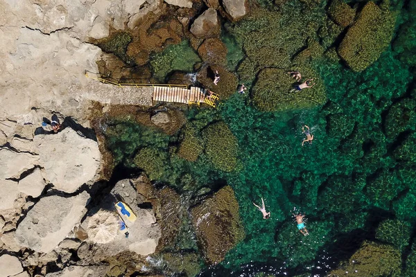 Top view on a rocky beach and turquoise sea with swimmers and snorkellis
