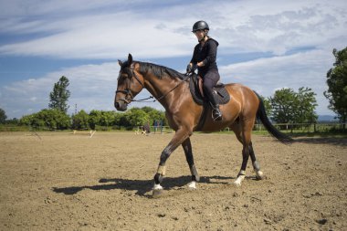 Binicilik okulunda miğferli ata binen kız.