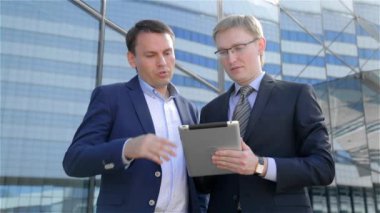 İki işadamları dijital tablet bilgisayar dokunmatik ekran, kullanarak çalışmaları hakkında konuşurken