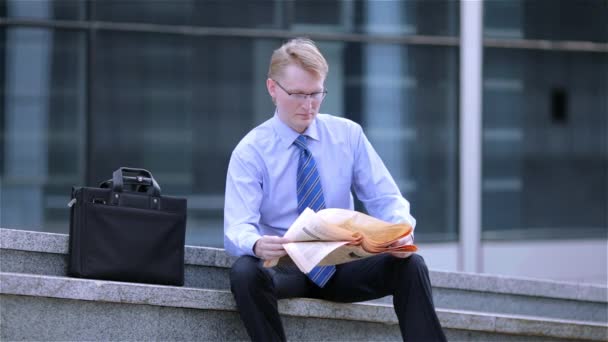 Ung affärsman läsa en tidning på gatan — Stockvideo