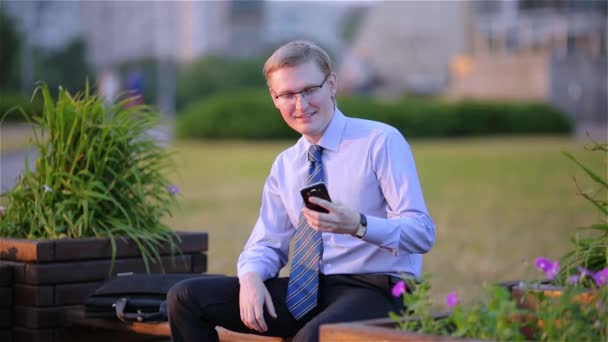 Молодой бизнесмен пишет смс на смартфоне — стоковое видео