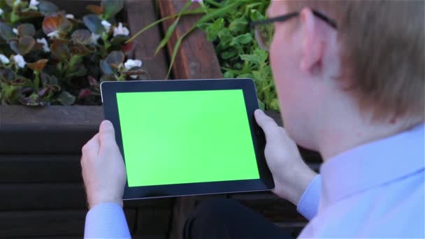 El hombre sostiene una tableta digital en blanco con una pantalla verde — Vídeos de Stock