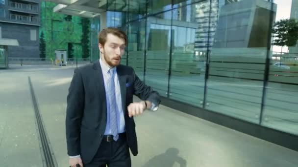 Hombre guapo está en un apuro, tarde, mirando el reloj (steadicam disparo ) — Vídeo de stock