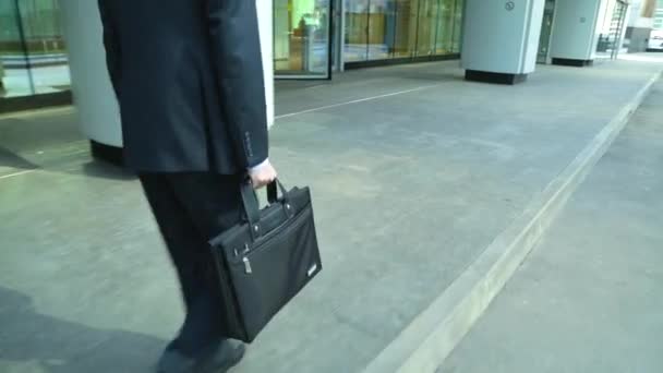 Nära skörd av affärsmannen fötter promenader i staden. Mannen pendlar till jobbet, han innehar en business portfölj i handen (steadicam sköt) — Stockvideo