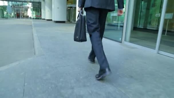 Feche a colheita de pés de homem de negócios que andam na cidade. Homem está viajando para o trabalho, ele tem uma pasta de negócios em sua mão (steadicam tiro ) — Vídeo de Stock