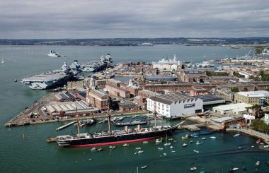 Güneşli bir yaz gününde Hampshire, Portsmouth 'daki Kraliyet Donanması tersanesinin hava görüntüsü. HMS Warrior, HMS Queen Elizabeth ve HMS Prince of Wales 'i de kapsayan hava manzarası..