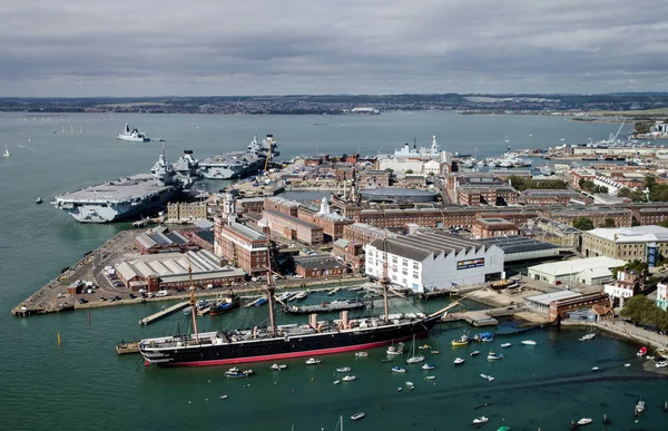 Güneşli bir yaz gününde Hampshire, Portsmouth 'daki Kraliyet Donanması tersanesinin hava görüntüsü. HMS Warrior, HMS Queen Elizabeth ve HMS Prince of Wales 'i de kapsayan hava manzarası..