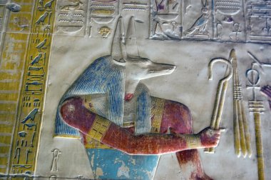 Close up of a painted hieroglyphic carving of the ancient egyptian god Anubis. Depicted with the head of a jackal, Anubis is the god of mummification and guardian of cemeteries. Decorated carving at the temple to Osiris at Abydos, Egypt. clipart