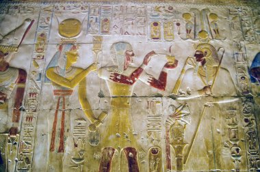 Abydos Tapınağı 'nın iç duvarına eski Mısır hiyeroglifleri kazınmış. Sol tarafta tanrıça Hathor 'u, sağ tarafta Tanrı Osiris' i Firavun Seti ile birlikte göstererek ortada bir adak sunuyorum..