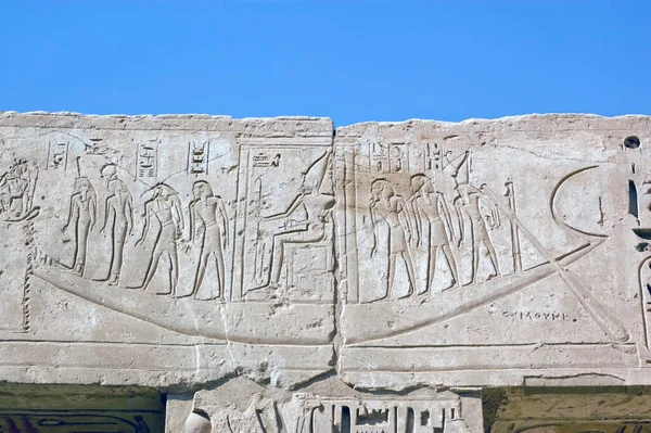 An ancient egyptian hieroglyphic carving of the sacred barque boat carrying the Pharoah and seven gods across the Nile to the afterlife. Lintel at the Temple of Medinet Habu on the west bank of the Nile at Luxor, Egypt.
