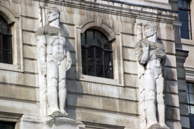 Sanatçı Sir Charles Wheeler 'ın iki dev erkek heykeli. Londra 'daki İngiltere Bankası' nın cephesi. Halka açık kaldırımlardan bakıldığında, 50 yıldan uzun süredir sergilenen kamu heykelleri.