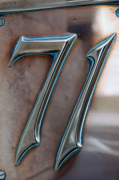 The number seventy one (71) embossed on a copper plate and on public display on the outside of an early victorian building in the City of London.