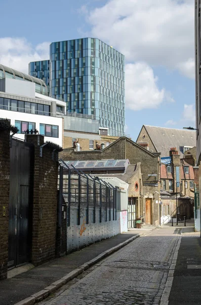 晴れた春の日には ロンドン中央部のカムデンのPentonville地区の狭い石畳の通りに沿ってご覧ください チャプターキングクロスの学生用宿泊施設の青い塔は 距離で顕著です — ストック写真