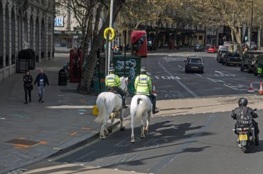Londra, İngiltere - 16 Nisan 2021: Güneşli bir öğleden sonra Londra 'nın orta kesimindeki Westminster, Aldwych civarında atlı polisler tarafından iki beyaz polis atına bindiriliyor.