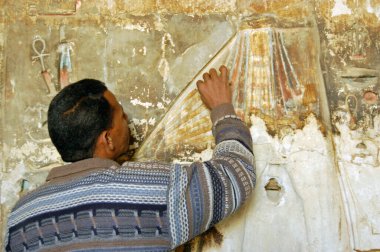 Lüksör, Mısır - 4 Ocak 2006: Mısır 'ın Luxor kentindeki Nil Nehri' nin Batı Şeria 'sındaki Medinet Habu antik Mısır tapınağında bir levrek yardım heykeli üzerinde çalışan bir restoratör.