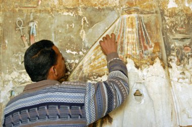 Luxor, Egypt - January 4, 2006: A restorer working on a painted bas relief sculpture in the Ancient Egyptian temple of Medinet Habu on the West Bank of the River Nile in Luxor, Egypt.