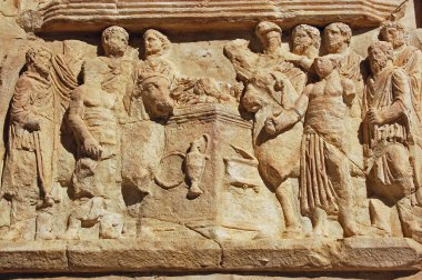 Antik Roma, tanrıları için kurban edilmek üzere olan hayvanları gösteren frizler oymuş. Kuzey Libya 'daki harabe büyük şehir Leptis Magna' da Septimius Severus Zaferi. 