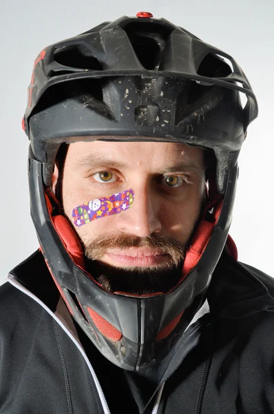 Yama ile yaralı adam. Kask ve sıfırdan yüzünde olan adam. Kask ve yüzünde küçük yara ile genç adam.