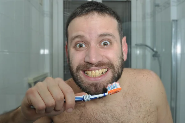 Dişlerini dikkat çekici bir genç adam. Dişleri sarı yıkama adam. Dişler sarı.