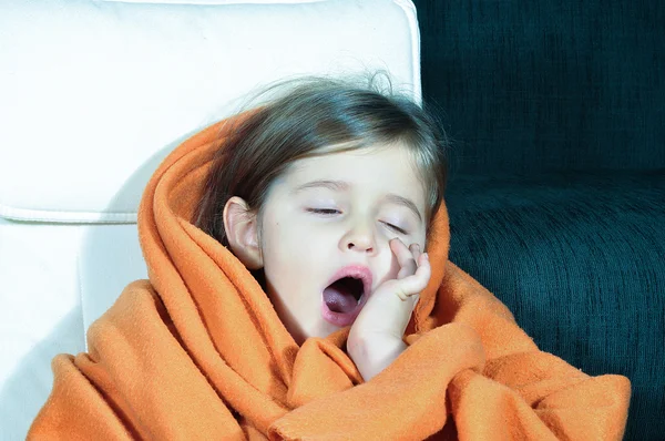 Niña bostezando. Niña enferma con manta y taza. Niño enfermo con los labios agrietados. Niña con gripe bebiendo su medicina . —  Fotos de Stock