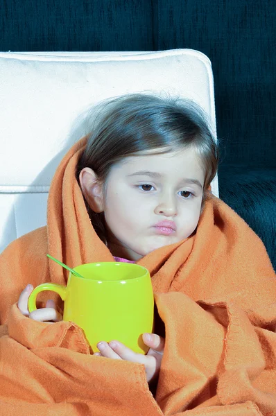 Battaniye ve Kupası ile hasta küçük kız. Hasta çocuk çatlamış dudaklar. İlacını içme gribi ile küçük kız.