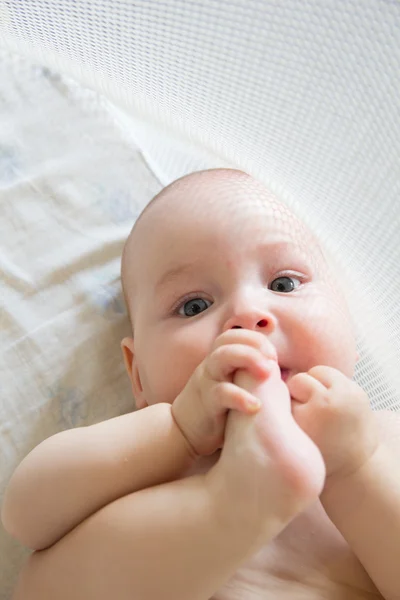Divertido bebé jugando con su pie —  Fotos de Stock