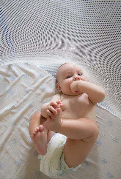 Bebé divertido en pañales jugando con un pie —  Fotos de Stock