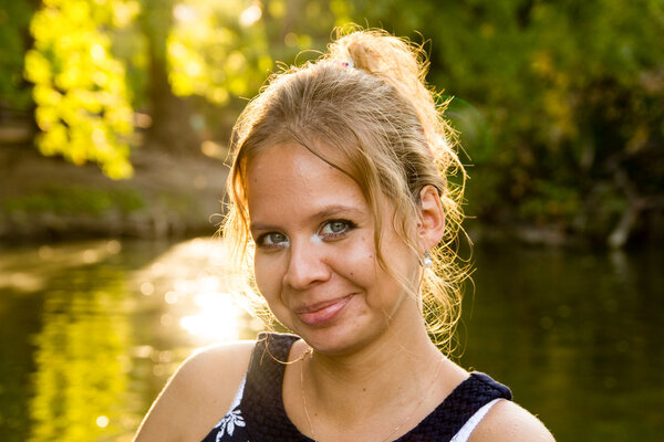 Портрет красивой девушки на фоне летнего парка и яркого солнца
