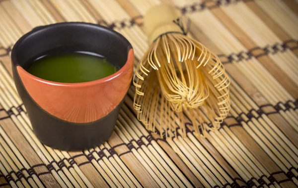 Grüner Tee in Tasse mit Bambusbesen lizenzfreie Stockfotos