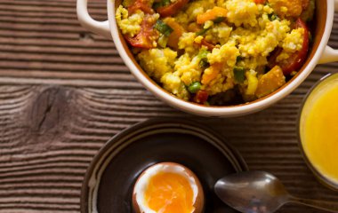 Haşlanmış pirinç ve olgun peynirli sebze, haşlanmış yumurta ve ahşap zemin üzerinde portakal suyu.