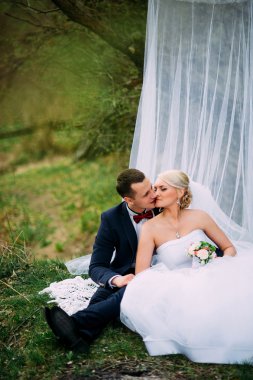 Zarif genç mutlu evlilik çift yeşil çimlere oturup 