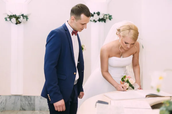 Bruid en bruidegom op de registratie van het huwelijk. De bruidegom kijkt naar de — Stockfoto