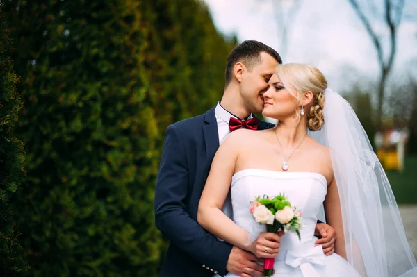 Bruid en bruidegom op bruiloft dag buitenshuis knuffelen op lente aard — Stockfoto