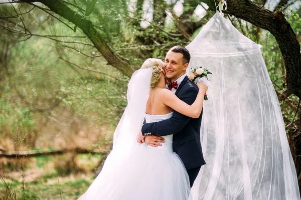 Elegante jovem casal casamento feliz está sentado na grama verde em — Fotografia de Stock