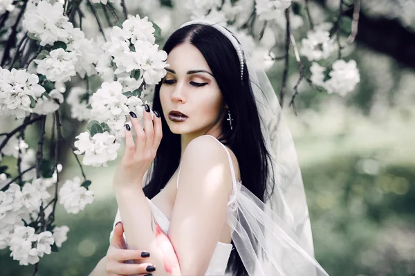 Retrato de una joven morena en el jardín de flores en el —  Fotos de Stock