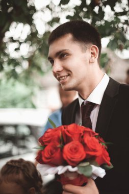 şık esmer elbiseli damat gülümseyen bir lüks bouq tutar