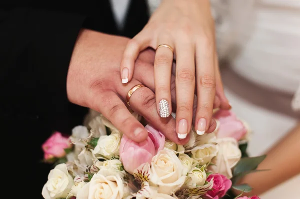 Mani di sposi con anelli su bouquet di nozze insoliti . — Foto Stock