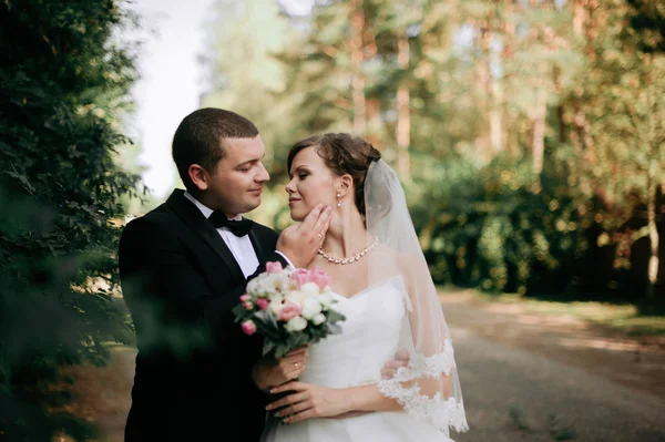 Elegante jovem casal casamento feliz está sentado na grama verde em — Fotografia de Stock