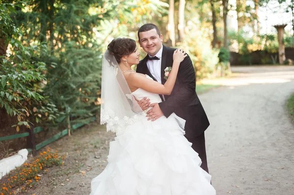 Elegante jovem casal casamento feliz está sentado na grama verde em — Fotografia de Stock