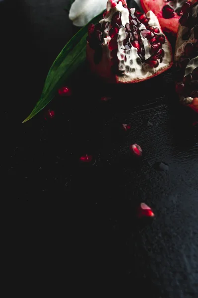 Deliciosas frutas de granada y lirios sobre fondo negro. Stil. — Foto de Stock