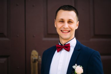  Mavi takım elbise ve papyon kırmızı kapıda giyen damat. 