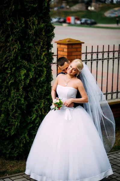 Braut und Bräutigam am Hochzeitstag umarmen sich im Freien an der Frühlingsnatur — Stockfoto
