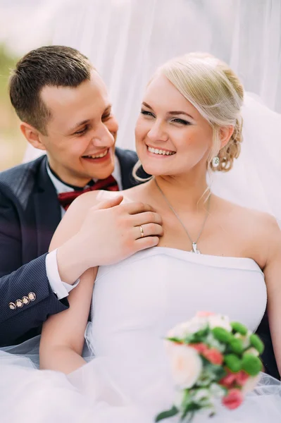 Elegante jovem casal casamento feliz está sentado na grama verde em — Fotografia de Stock