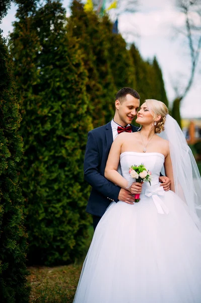 Bruid en bruidegom op bruiloft dag buitenshuis knuffelen op lente aard — Stockfoto