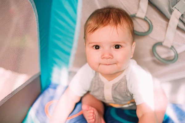 Cute little baby boy playing in colorful playpen, indoors. Beautiful child having fun at nursery. — Stock Photo, Image