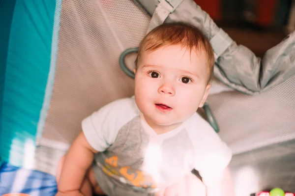 Bonito menino brincando em playpen colorido, dentro de casa. Criança bonita se divertindo no berçário . — Fotografia de Stock