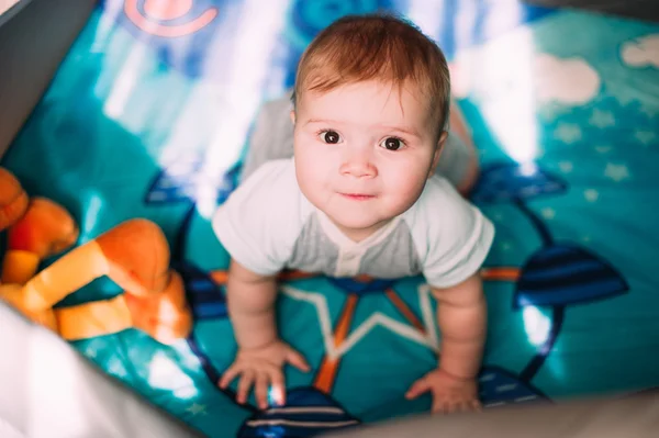 Cute little baby boy playing in colorful playpen, indoors. Beautiful child having fun at nursery. — Stock Photo, Image