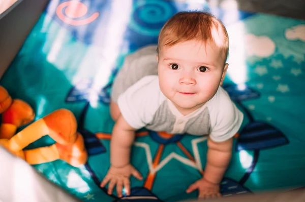 Cute little baby boy playing in colorful playpen, indoors. Beautiful child having fun at nursery. — Stock Photo, Image