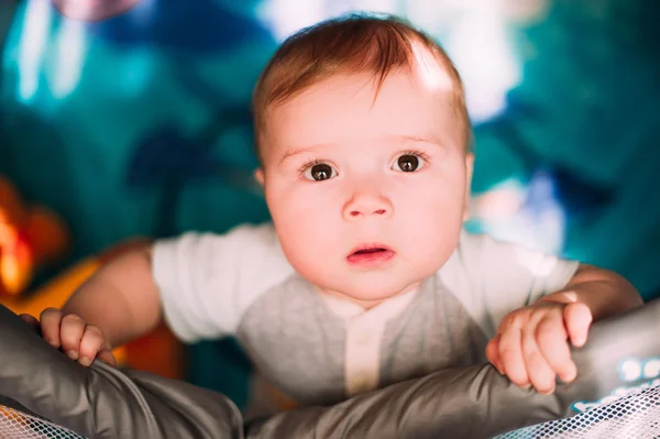 Cute little baby boy playing in colorful playpen, indoors. Beautiful child having fun at nursery. — Stock Photo, Image